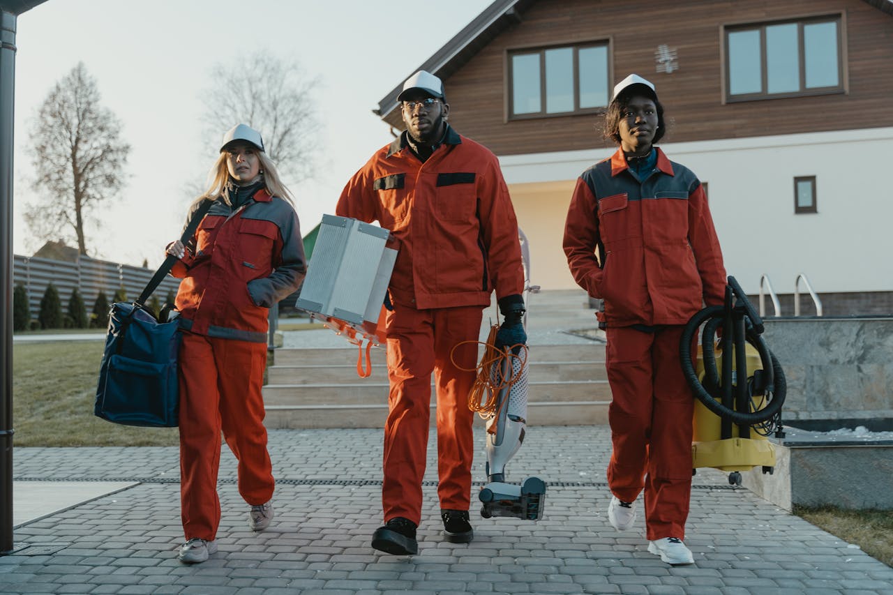 A diverse team of professional cleaners walking outdoors in uniform, holding tools.